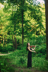 Beautiful girl in a black dress plays the violin in the woods © Dmitriy Shipilov