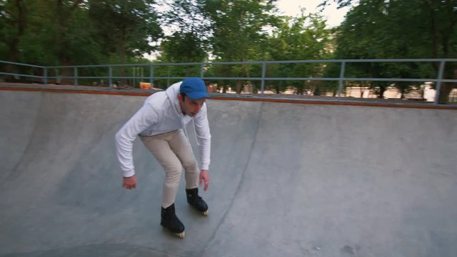 Aggressive Inline roller skater doing tricks in concrete skatepark outdoors during sunset