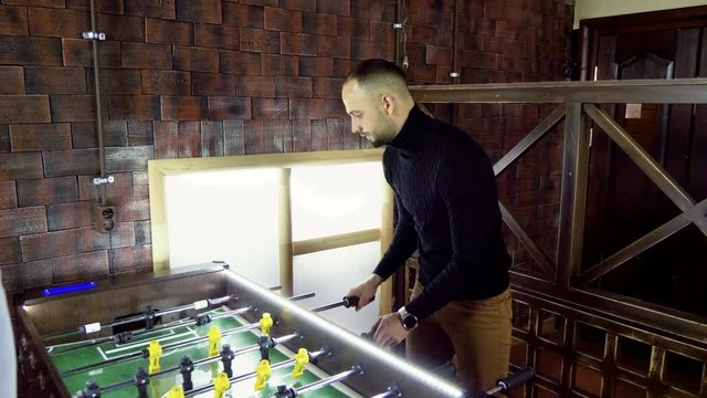 Sport, game concept. Foosball. One man playing a table football or kicker with miniature players. 4K