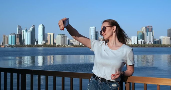 Outdoor portrait of young attractive female in stylish outfit making a selfie. Phone camera POV.