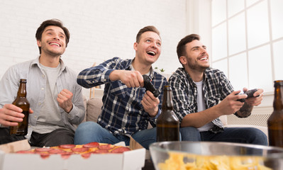 Excited men playing video game, having home party