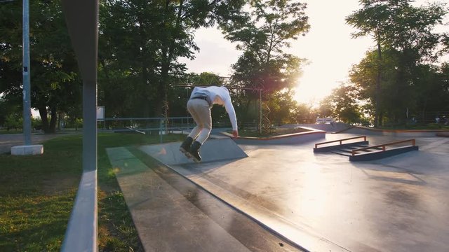 Aggressive Inline roller skater doing tricks in concrete skatepark outdoors, slow motion, tracking shot