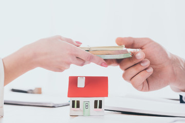 partial view of manager taking money from woman near house model