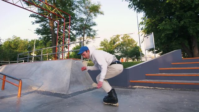 Aggressive Inline roller skater doing tricks in concrete skatepark outdoors, slow motion