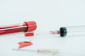 test tube with blood and syringe on white surface