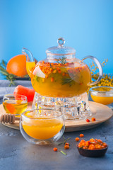 A bright orange teapot on a blue background and a stone table