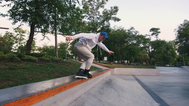 Aggressive Inline roller skater doing tricks in concrete skatepark outdoors, slow motion