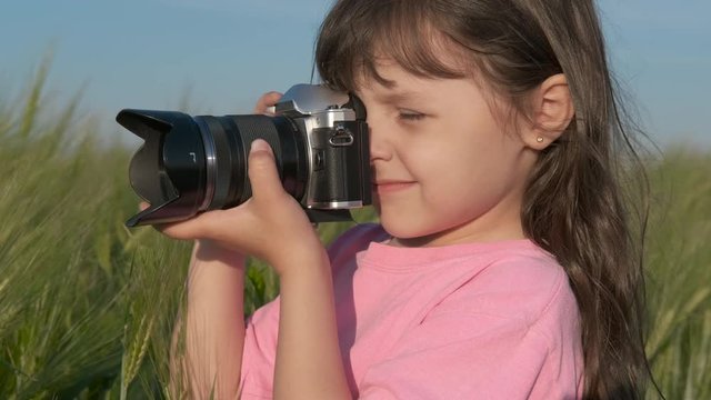 Portrait of a child with a camera. A little girl takes pictures in the summer in nature.