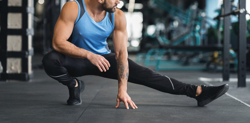 Fototapeta premium Man stretching leg before workout at gym