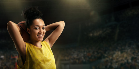 Female basketball player with ball on big professional arena 