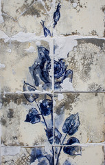 Detail of a blue rose on ceramic tiles wall from damaged facade of old house in Portugal.