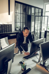 Mature dark-haired businessman checking his e-mail on computer