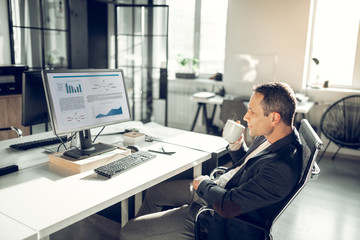 CEO drinking some tea while reading news on computer