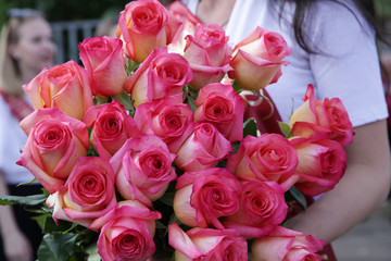a large bouquet of beautiful pink roses with half-open buds in their hands at the feast. Holiday concept.