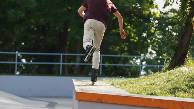 Aggressive Inline roller skater doing tricks in concrete skatepark outdoors with beautiful background, super slow motion