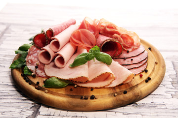 Food tray with delicious salami, pieces of sliced ham, sausages,salad and vegetable. Meat platter with selection