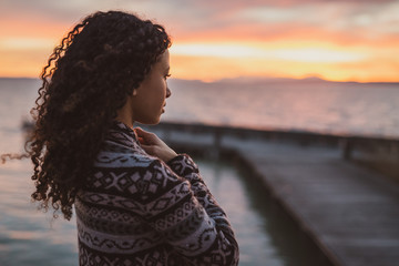 Thoughtful evening mood with a young African American woman standing on the promenade by the lake...
