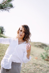 Naklejka premium Beautiful young woman in white near a tree in rural sunny landscape background in summer. Tender happy woman in enjoying nature. Soft focus
