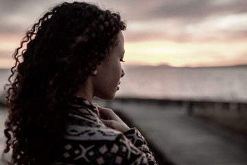 Thoughtful evening mood with a young African American woman standing on the promenade by the lake...