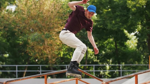 Aggressive Inline roller skater doing tricks in concrete skatepark outdoors with beautiful background, super slow motion