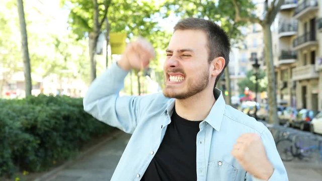 Excited man celebrating success in the street looking away