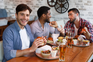 Mates Spending Time In Pub, Eating Burgers And Drinking Beer