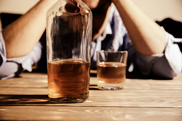 Alcoholic addict. Man near the table with alcohol and a glass. Dangerous habit. Unhealthy life concept. Social problem.