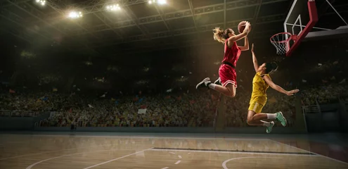 Keuken spatwand met foto Female basketball players fight for the ball. Basketball player makes slam dunk on big professional arena during the game © Alex