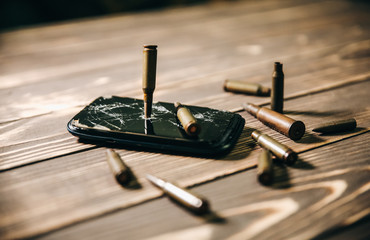 Crashed black smartphone with a bullet on white background. Broken lcd touch screen. Information technology photo. War concept.