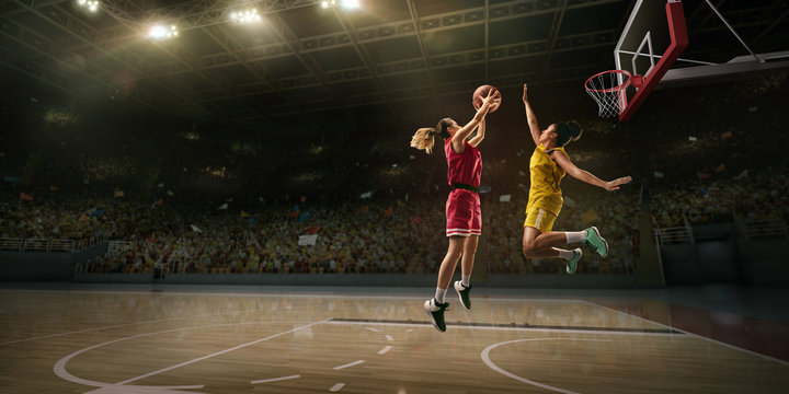 Female basketball players fight for the ball. Basketball player makes slam dunk on big professional arena during the game