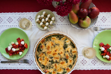 A gourmet lunch: spinach pie with cheese, a bowl of fruits, a salad and wine.