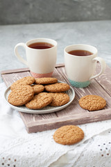 A tasty snack: two cups of tea and a plate of cookies.