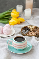 A tasty snack: a cup of coffee, a plate of zephyr and a box of sweets.