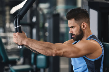 Fototapeta na wymiar Focused athlete exercising on training machine at gym