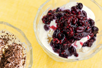 Ice cream dessert with chocolate and currant jam. Top view on yellow table-napkin. Selective focus