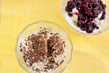 Ice cream dessert with chocolate and currant jam. Top view on yellow table-napkin. Selective focus