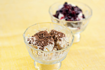 Ice cream dessert with chocolate and currant jam on yellow table-napkin. Selective focus