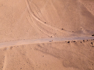 Fototapeta na wymiar Aerial view of a desert landscape on the island of Lanzarote, Canary Islands, Spain. Road that crosses a desert. A man with a orange t-shirt walking in a desert land