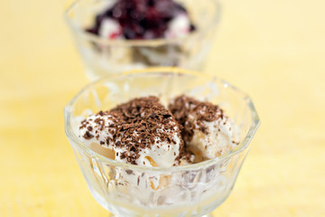 Ice cream dessert with chocolate and currant jam on yellow table-napkin. Selective focus