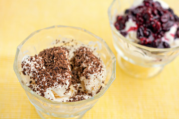Ice cream dessert with chocolate and currant jam on yellow table-napkin. Selective focus