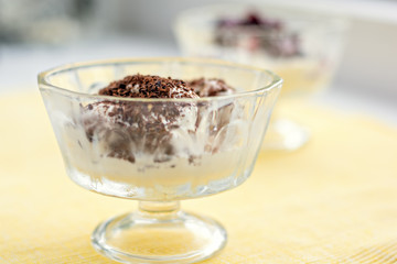Ice cream dessert with chocolate and currant jam on yellow table-napkin. Selective focus