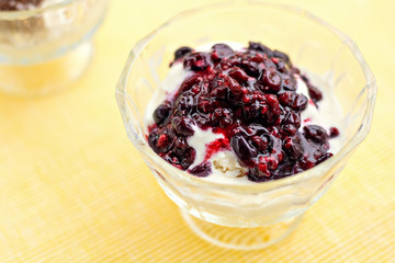 Ice cream dessert with chocolate and currant jam on yellow table-napkin. Selective focus