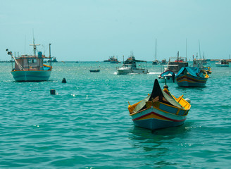 Fototapeta premium Colorful poats in aqua blue water. Marsaxlokk malta