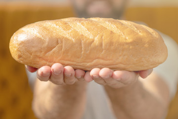 Male hands holding freshly baked wheaten bread closeup