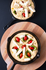 Food concept rising dough for Homemade organic Focaccia in skillet iron pan on black background with copy space