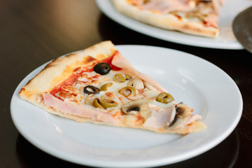 Mushroom pizza slice on white ceramic plate over the table.