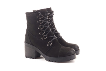 Female Legs in Classic Black and White Sneakers. Legs are Raised Upwards and Dangle from Side to Side. Grey Background. Classic Shoes. Healthy Lifestyle