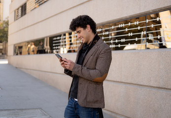 Young attractive happy hipster man talking on smart phone in european city