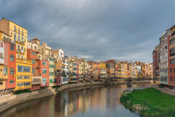 Naklejka na ściany i meble Colorful yellow and orange houses reflected in water in river Onyar. Girona, Catalonia, Spain.
