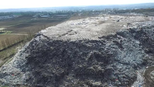 Aerial top drone view of large garbage pile, trash dump, landfill, waste from household dumping site, excavator machine is working on a mountain of garbage. Consumerism and contamination concept